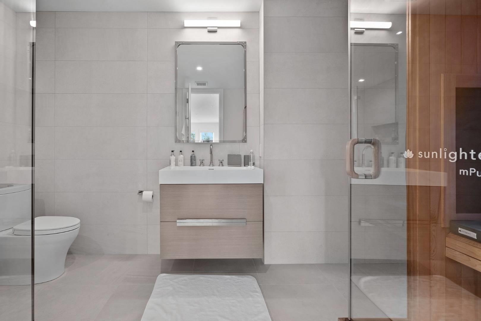 Bathroom featuring tile patterned floors, toilet, vanity, a shower with shower door, and tile walls