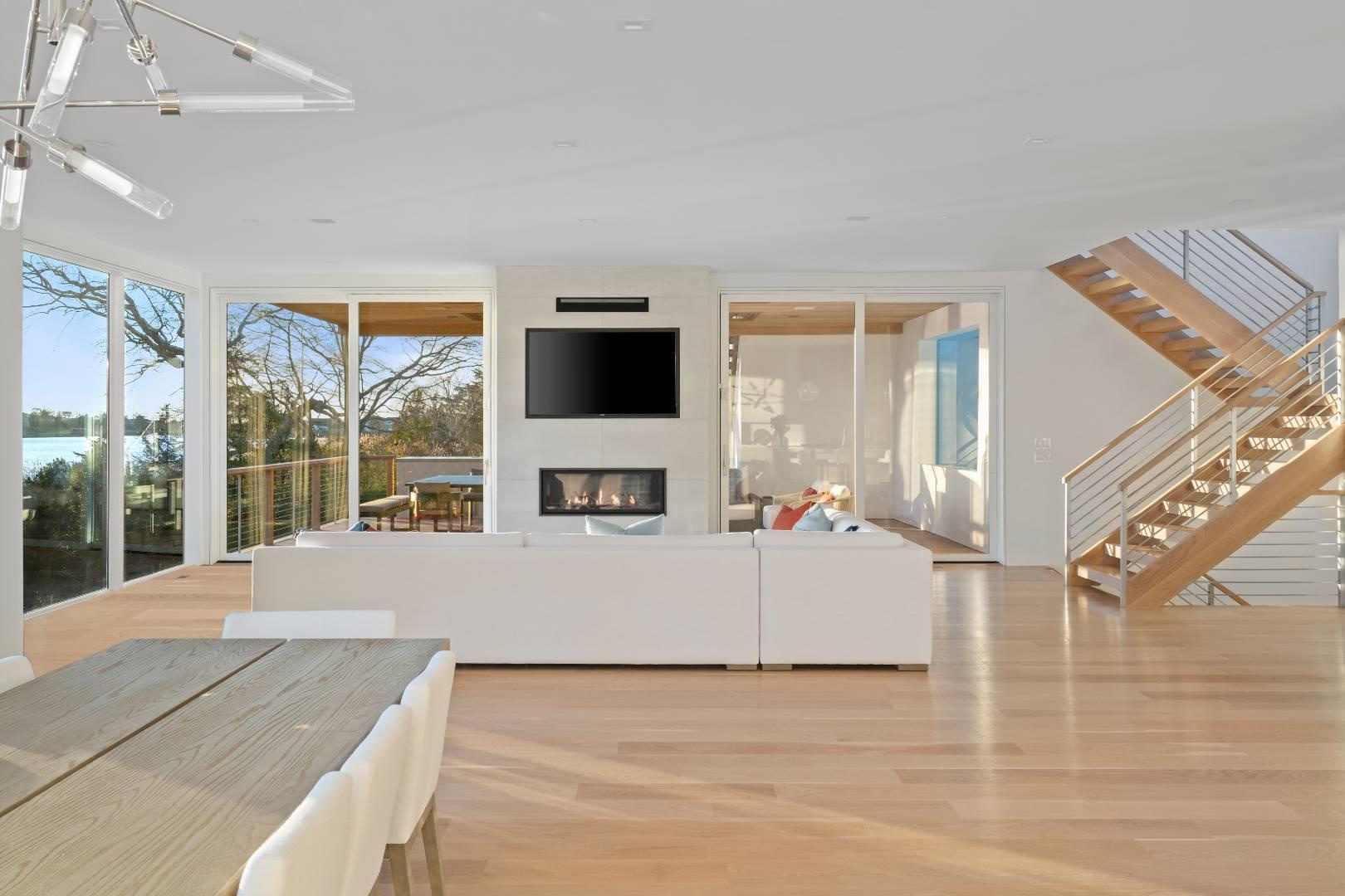 Living room with a large fireplace, light wood-type flooring, floor to ceiling windows, and an inviting chandelier