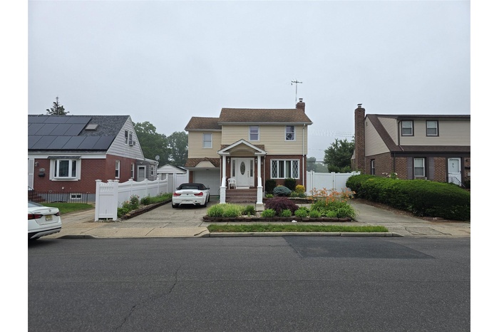 View of front of house featuring a chimney, driveway, a garage, and brick siding