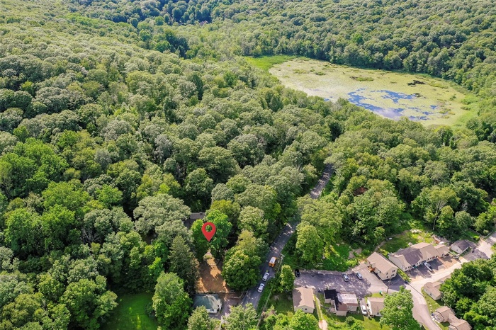 Drone / aerial view of a heavily wooded area and a nearby body of water