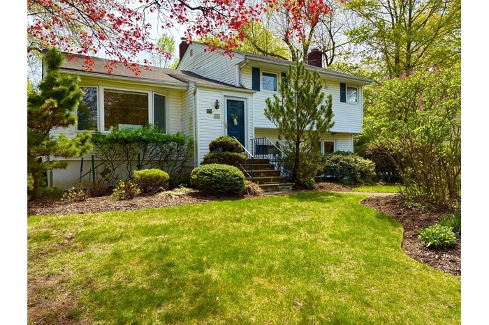 Tri-level home featuring a front lawn and a chimney