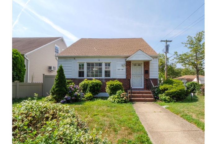 View of front of home featuring brick siding and roof with shingles