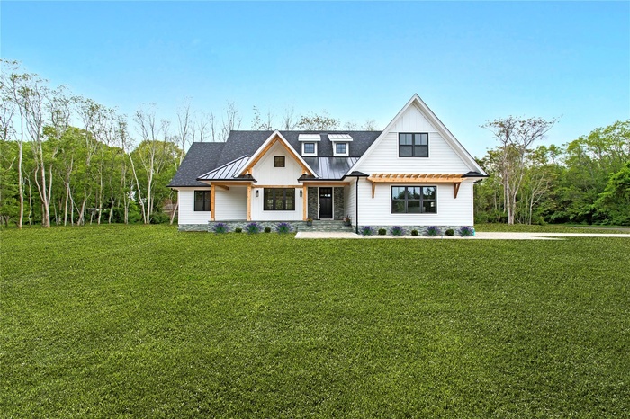 Modern inspired farmhouse with a front lawn, metal roof, a standing seam roof, and board and batten siding