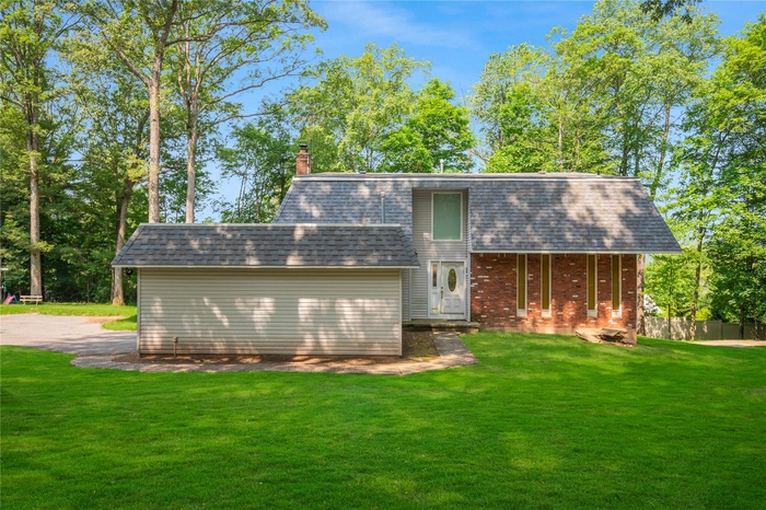 Rear view of house featuring a chimney and a shingled roof
