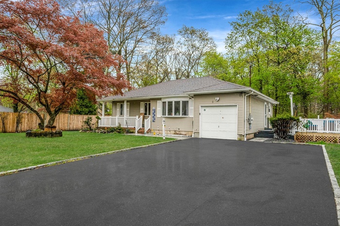 Single story home with a porch, a front lawn, a garage, aphalt driveway, and fence