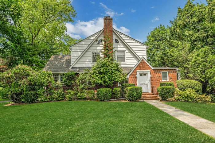 Tudor-style house with a front lawn, brick siding, and a chimney