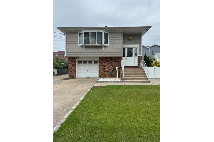 Tri-level home with an attached garage, concrete driveway, and brick siding
