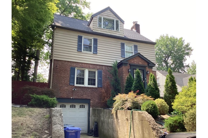 View of front of house featuring a chimney, a garage, and brick siding