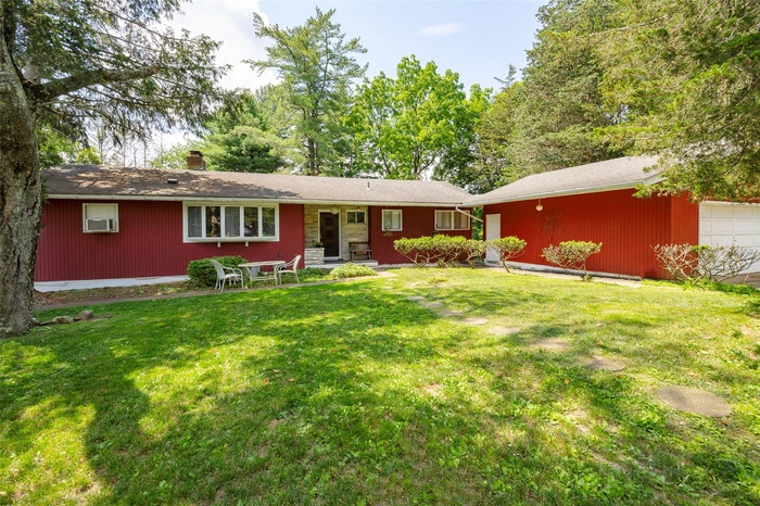 View of front of house with a garage, a front yard, and a chimney