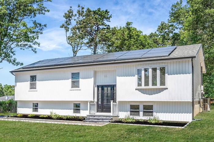 View of front of property with a front lawn and roof mounted solar panels