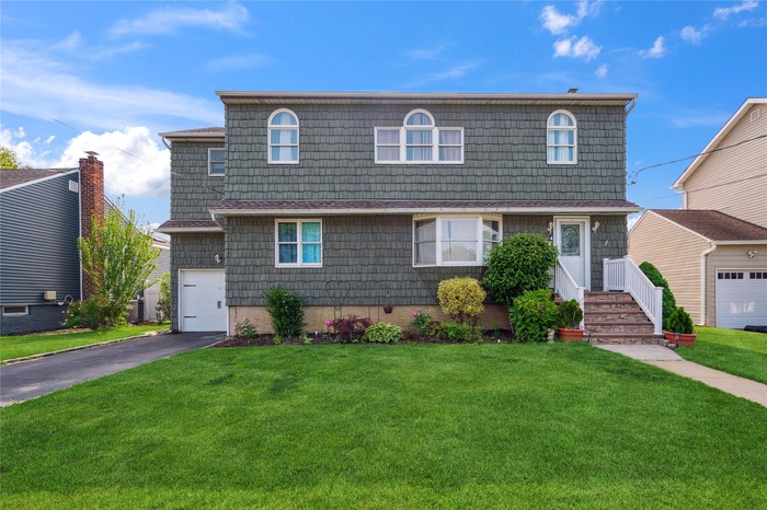 View of front facade featuring driveway and a front lawn