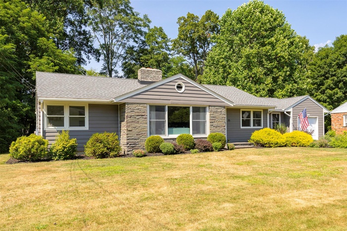 Ranch-style house with roof with shingles, a chimney, and a front lawn