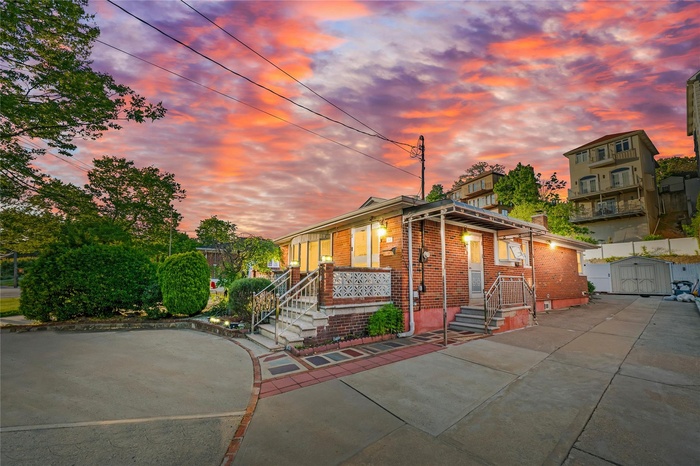 View of front of house featuring brick siding, a chimney, and a gate
