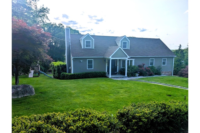 Cape cod-style house featuring a front yard, a chimney, and roof with shingles