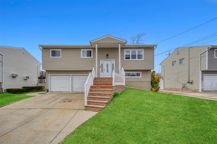 Bi-level home with an attached garage, a front yard, and concrete driveway