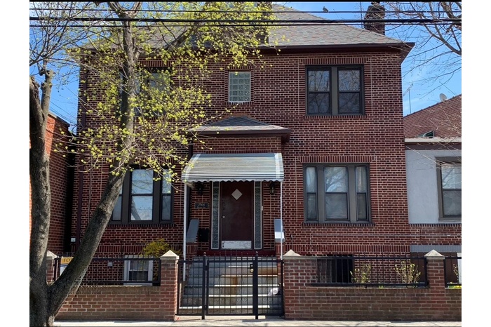 View of front of house featuring a chimney, a fenced front yard, brick siding, and a shingled roof