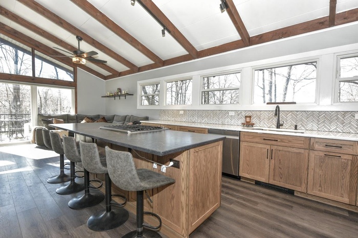 Kitchen featuring tasteful backsplash, a sink, a breakfast bar area, dishwasher, and vaulted ceiling with beams