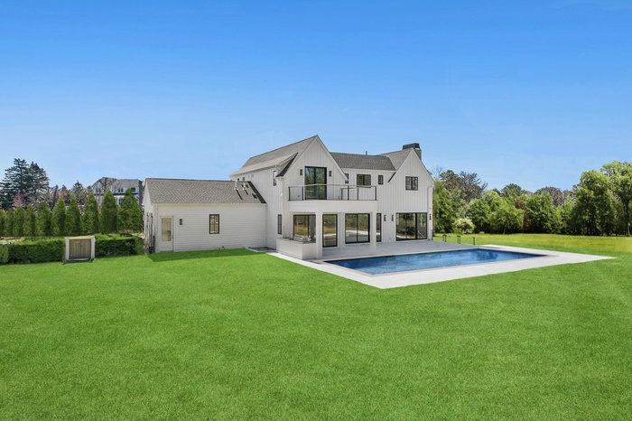 Rear view of property with a balcony, an outdoor pool, a yard, and a patio