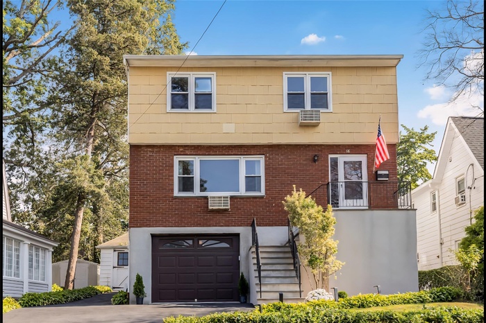 Colonial house featuring an attached garage, brick siding, stairs, and driveway