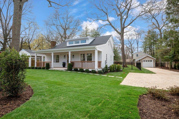 View of front of home featuring driveway, covered porch, an outdoor structure, fence, and a garage