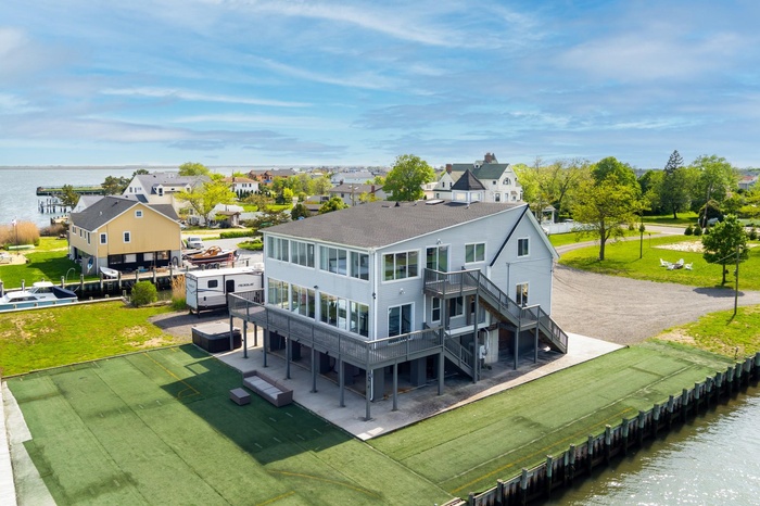 Rear view of house with stairs, a deck with water view, a yard, and a patio