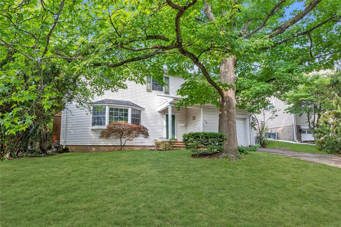 View of front of house featuring a garage, a front lawn, and driveway