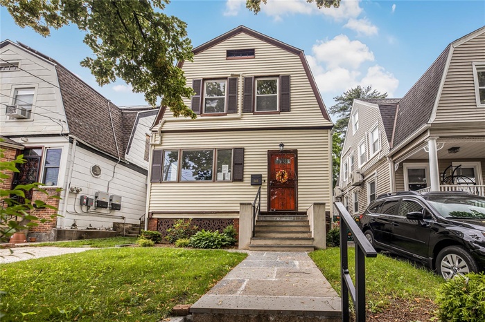 Colonial inspired home with entry steps, a gambrel roof, and front yard. Bluestone pavers.