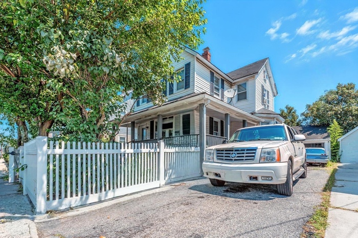 View of front of house with covered porch, a fenced front yard, and a chimney