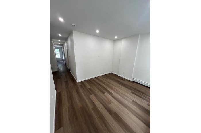 Basement featuring a baseboard radiator, dark wood-style flooring, and recessed lighting