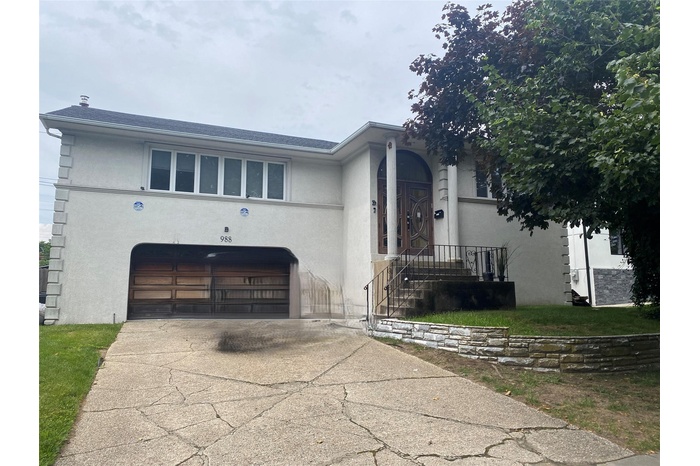 View of front of home with stucco siding, concrete driveway, and an attached garage