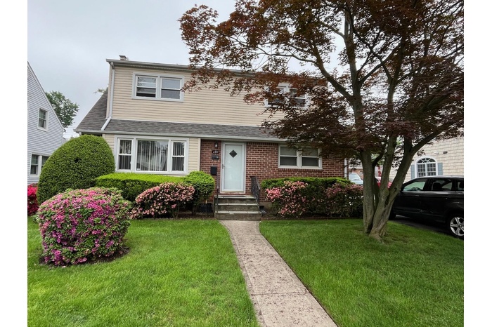 View of front of home featuring a front lawn, entry steps, brick siding, and a shingled roof