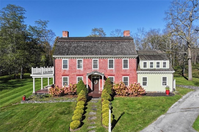 View of front of house featuring a chimney, a front lawn, and a deck