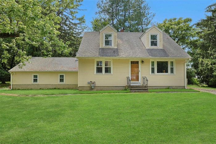 Cape cod home featuring a front yard, roof with shingles, and entry steps