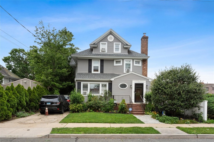 Traditional style home with a shingled roof, a chimney, and concrete driveway