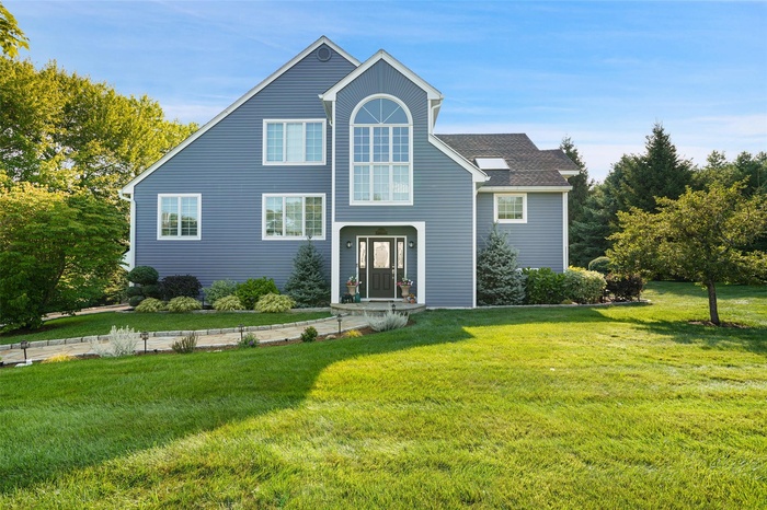 Traditional-style home with a front lawn and roof with shingles