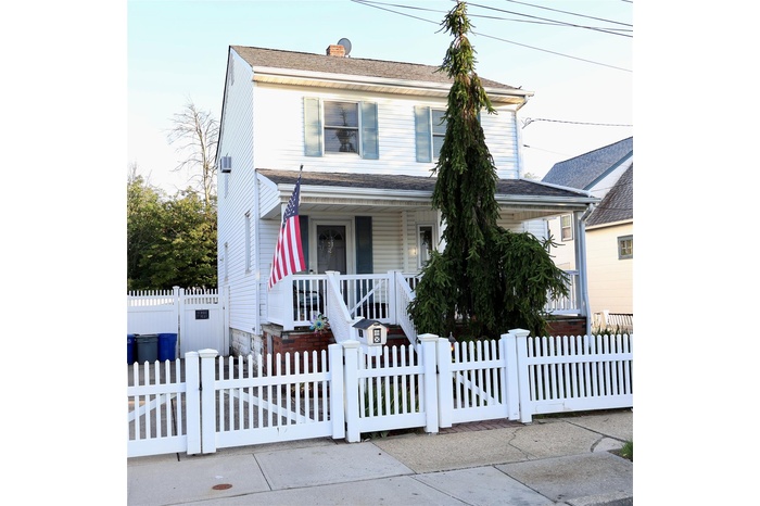 View of front of house with a porch, a gate, a fenced front yard, and a chimney