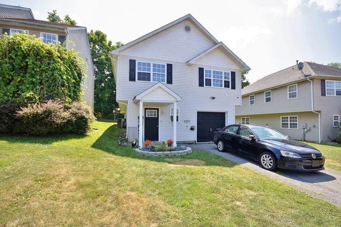 Traditional-style home featuring driveway, a garage, and a front lawn