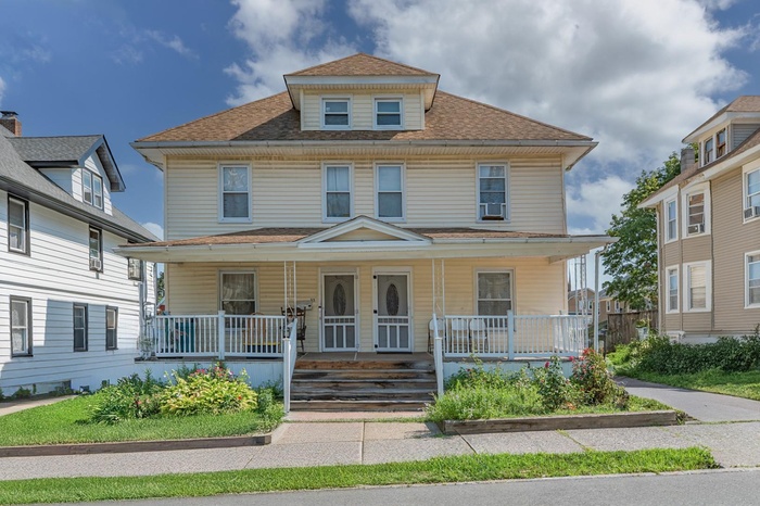 Traditional style home featuring a shingled roof and a porch