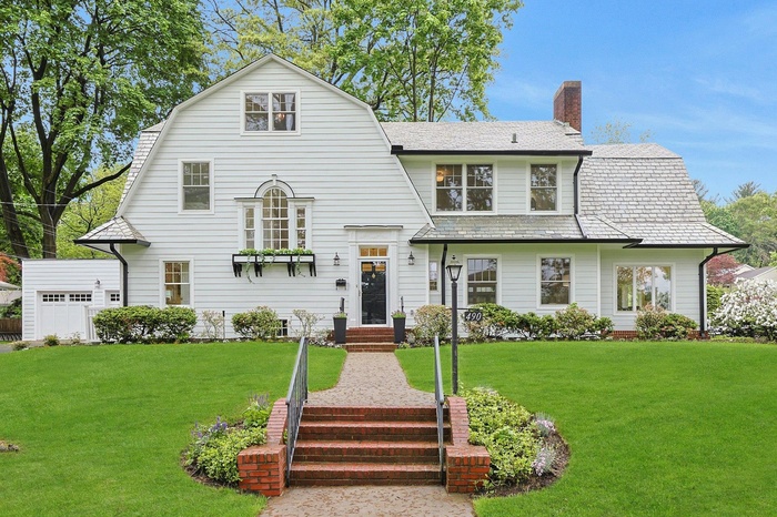 Dutch colonial with a chimney, a front lawn, a high end roof, and a gambrel roof