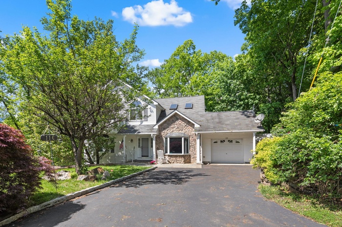 View of front of house featuring stone siding, driveway, and an attached garage
