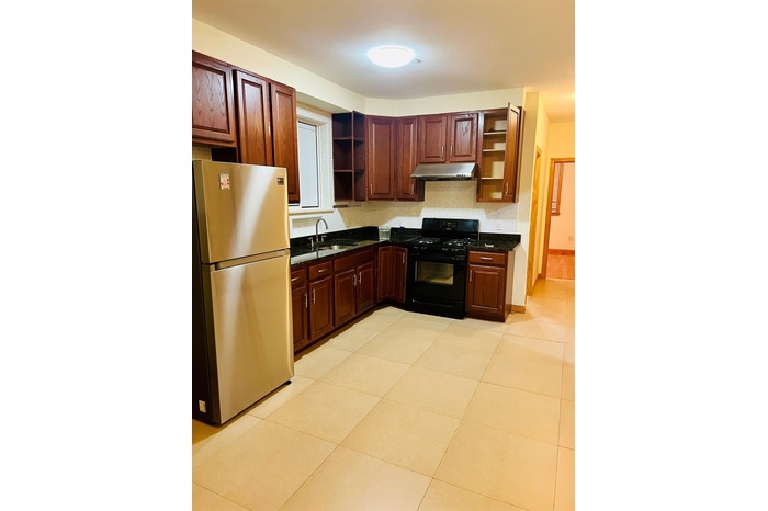 Kitchen featuring freestanding refrigerator, open shelves, black gas range oven, and under cabinet range hood
