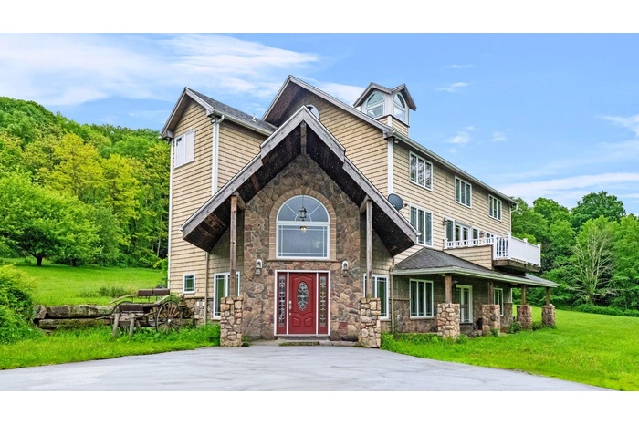 View of front of house featuring stone siding and a front lawn