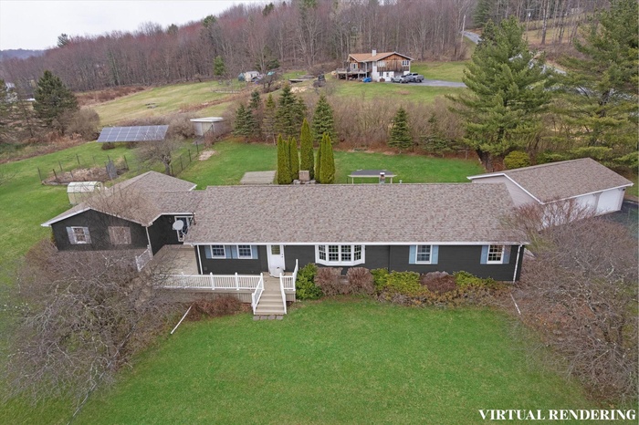 Aerial view of property and surrounding area with a heavily wooded area