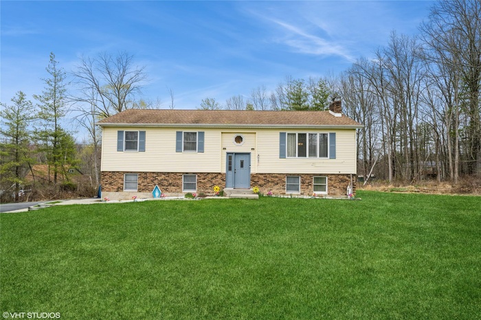 Split foyer home with a front yard, brick siding, and a chimney