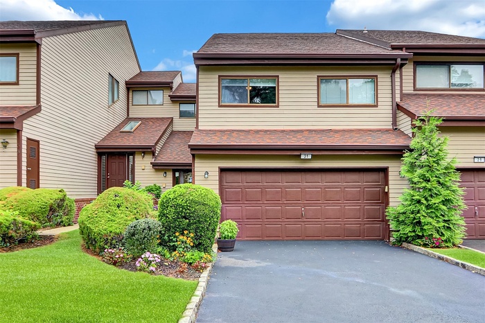 View of front of house featuring a shingled roof, driveway, an attached garage, and a front yard