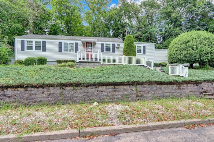 View of front of property featuring view of scattered trees and roof with shingles
