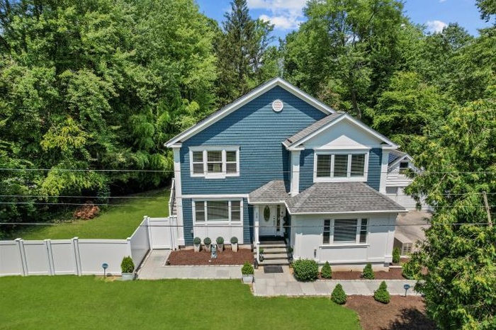 View of front of house with a fenced backyard and a view of trees