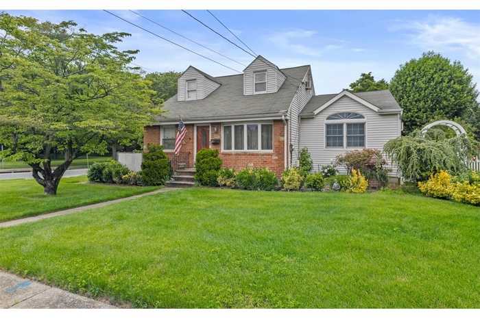 Cape cod-style house featuring brick siding and a front lawn