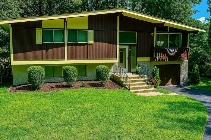 Bi-level home featuring a front yard, an attached garage, and asphalt driveway