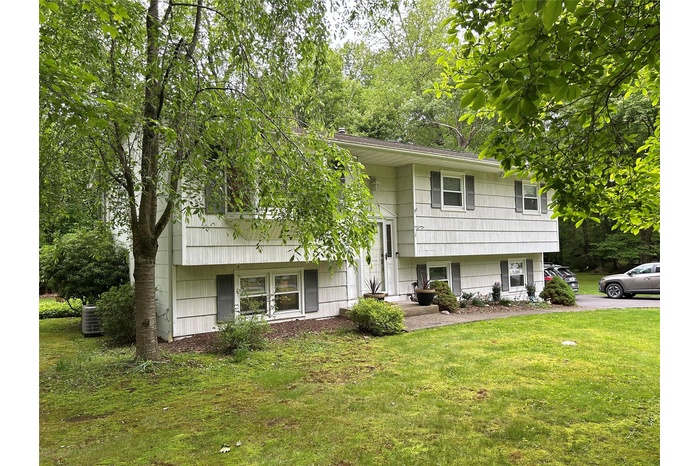 View of front facade featuring a front lawn and central air condition unit
